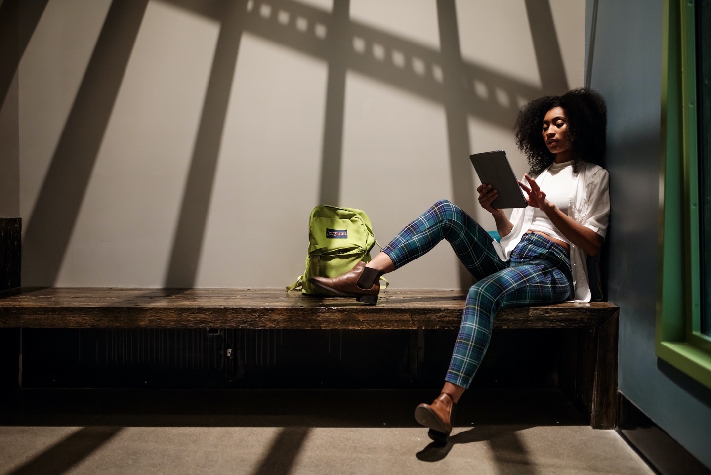 Stylish woman holding tablet & sitting on a bench