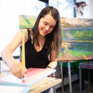 Smiling student painting on a canvas