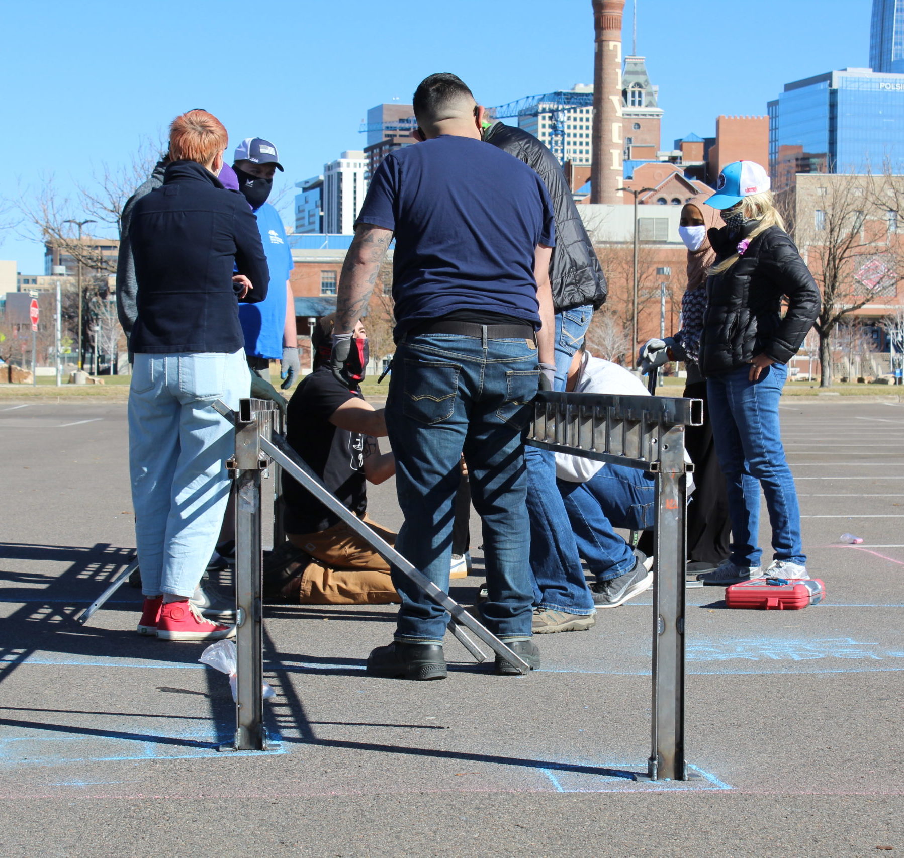 Individuals working on a large metal piece outside