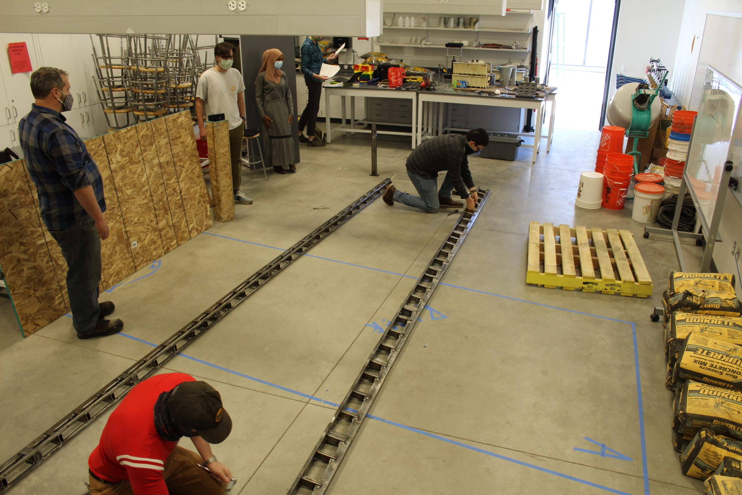 Individuals working on long metal pieces