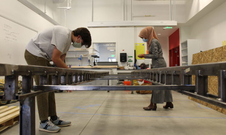 Man and woman in a hijab working on a large metal structure