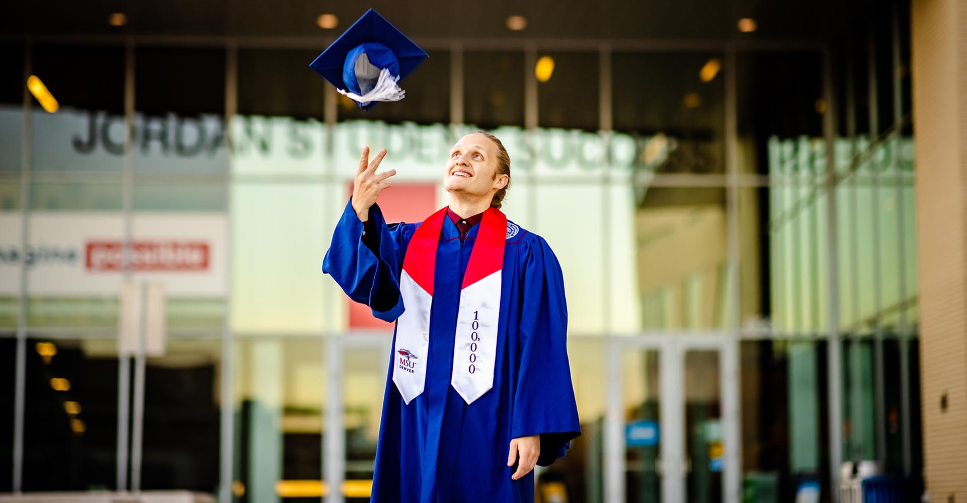 100,000th graduate Branden Ingersoll throwing cap in the air