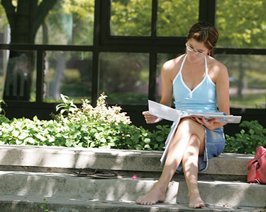 Studying student with no shoes surrounded by plants