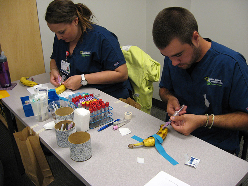 Students practicing phlebotomy on bananas.