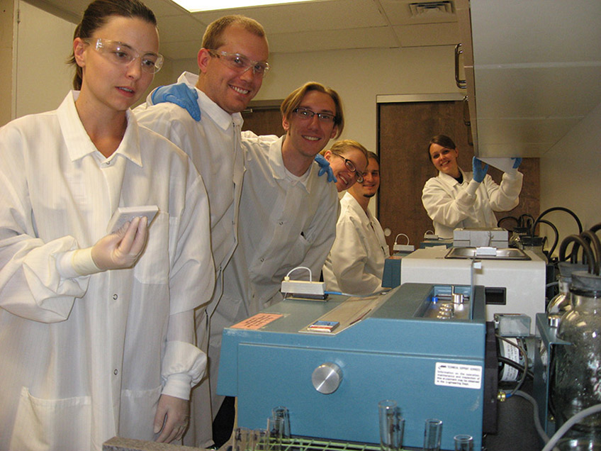 Students reading tests results on spectrophotometers in chemistry lab.