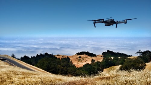 A drone hovers over grassy hills