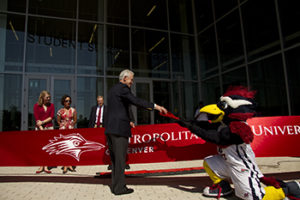 Rowdy Roadrunner mascot handing scissors to president Jordan in front of the newly-opened Student Success Building