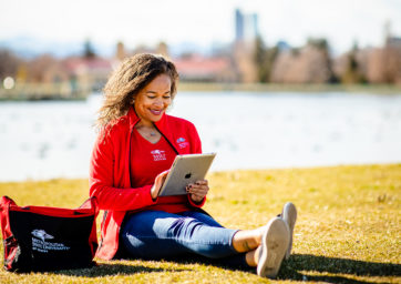 Student reading tablet outside.