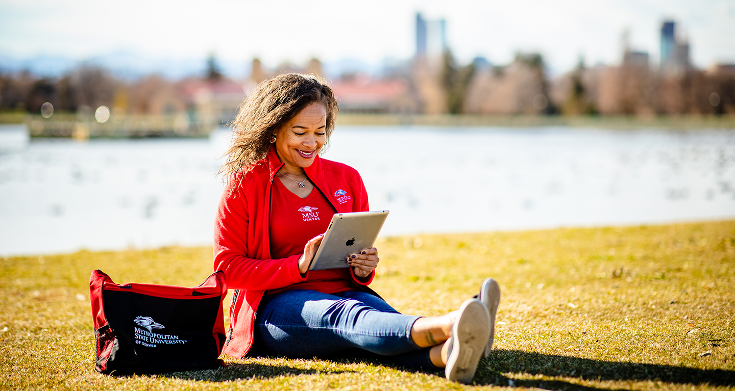 Student reading tablet outside.