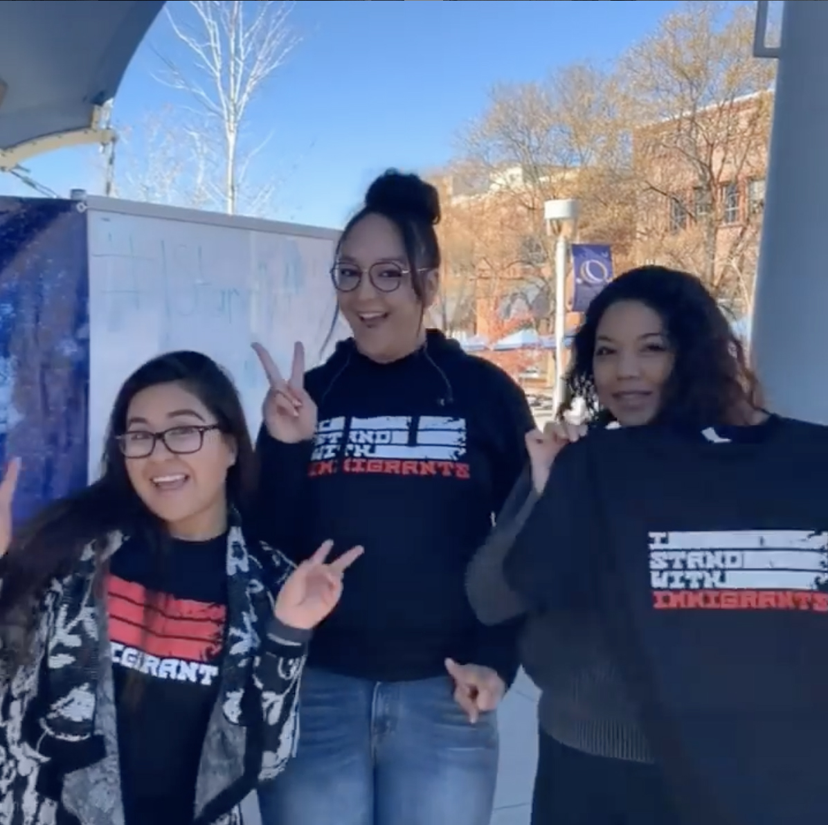 Three females holding or wearing shirts that say 