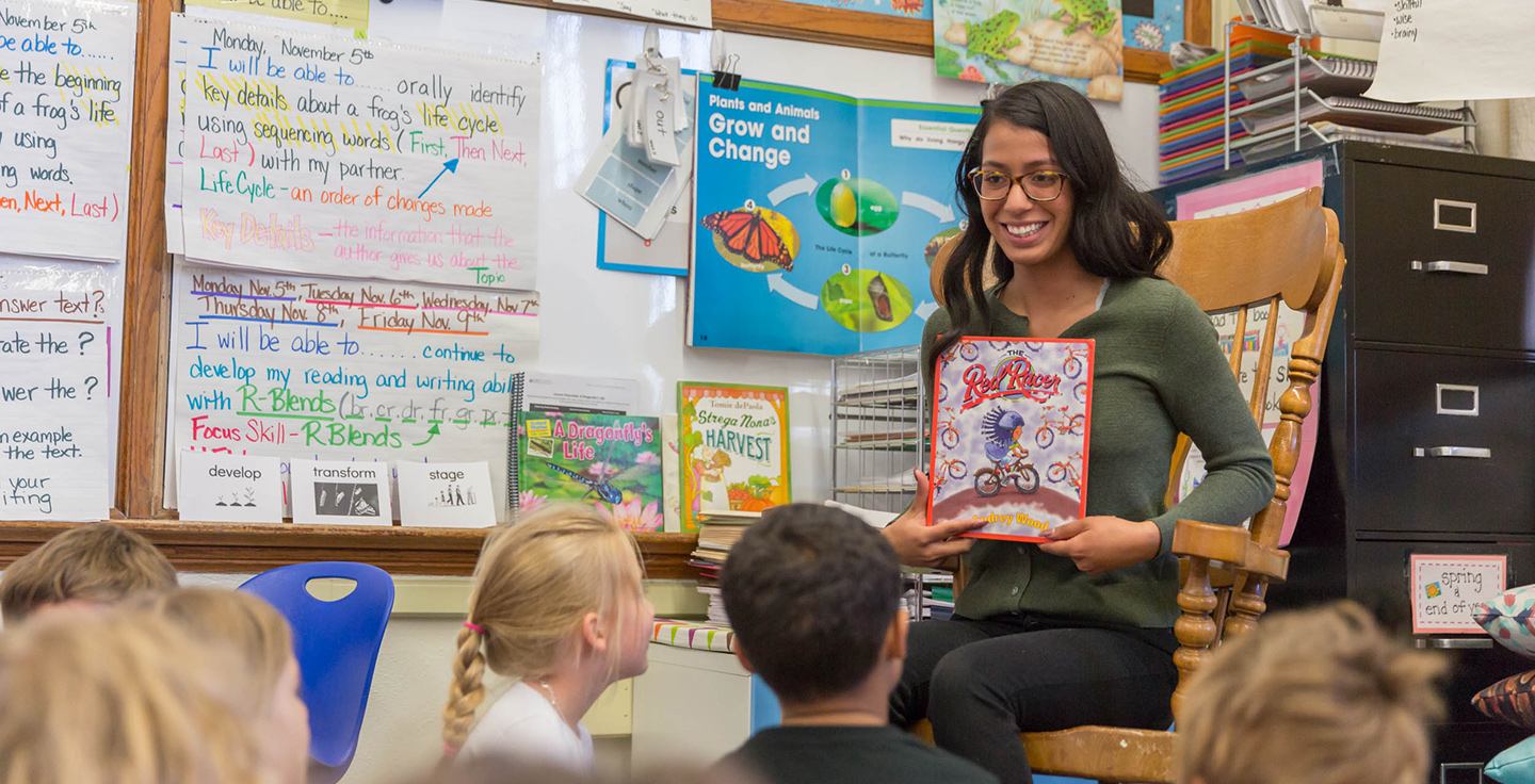 MSU Denver student Idalee Nunez reading a book to young children in a classroom.