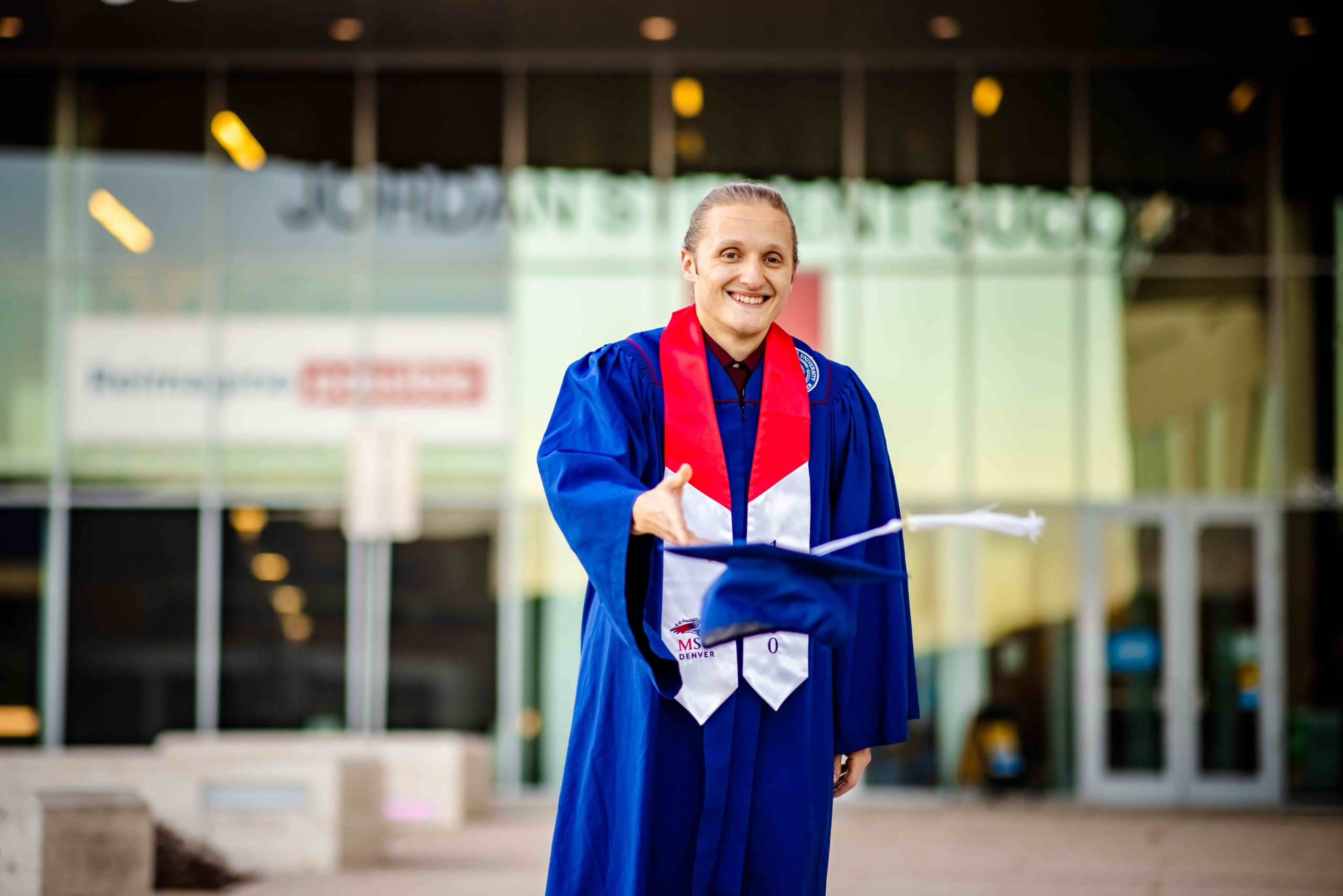 Branden Ingersoll the 100,000th graduate in his regalia at the Student Success Building.