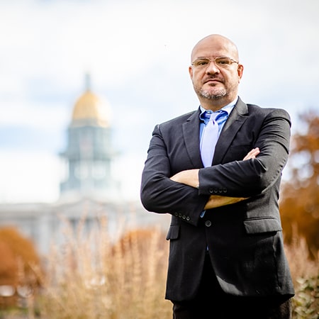 Legislator José Flores poses in front of the Colorado State Capitol building.