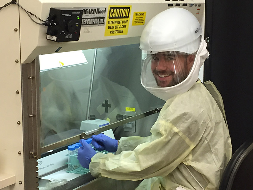 Student working under a biohazard hood in PPE