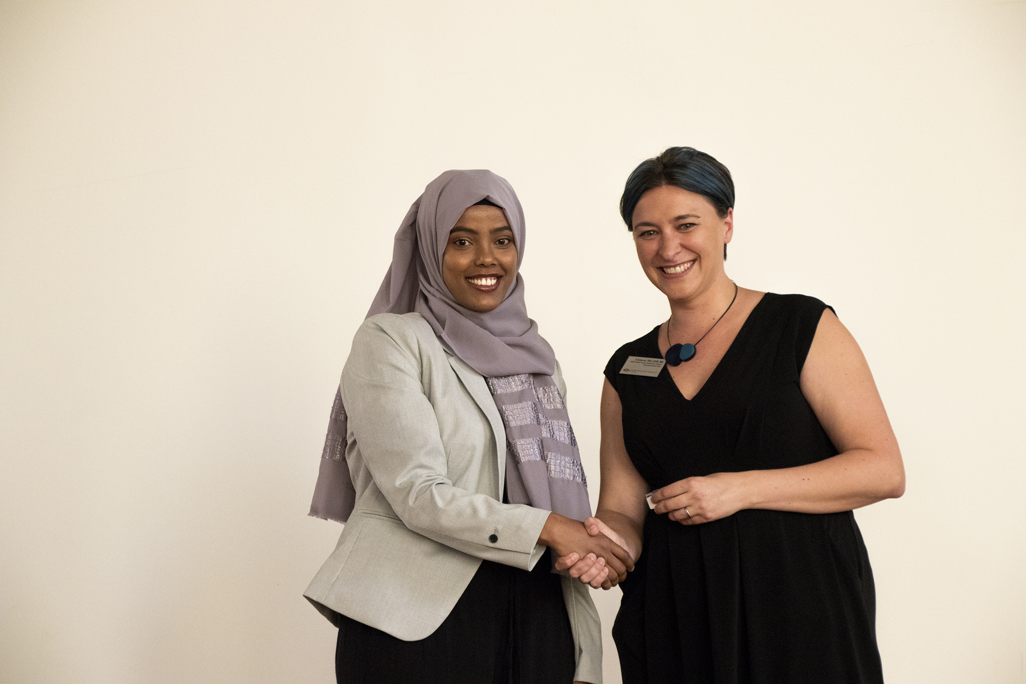 Two women shaking hands at the BSW Pinning ceremony