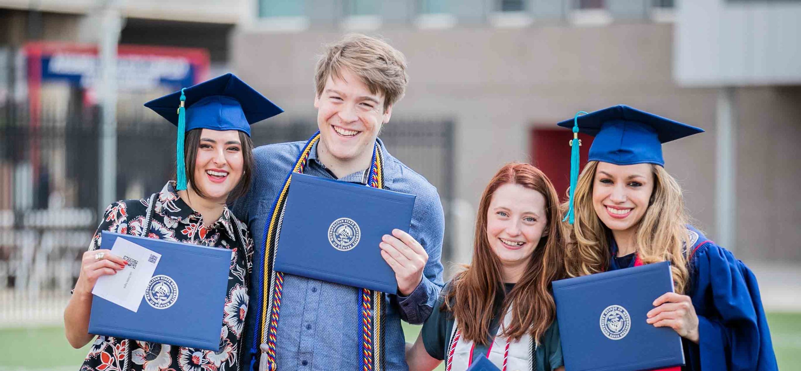 A group of graduates showing off their diploma covers as they walk towards the stage.