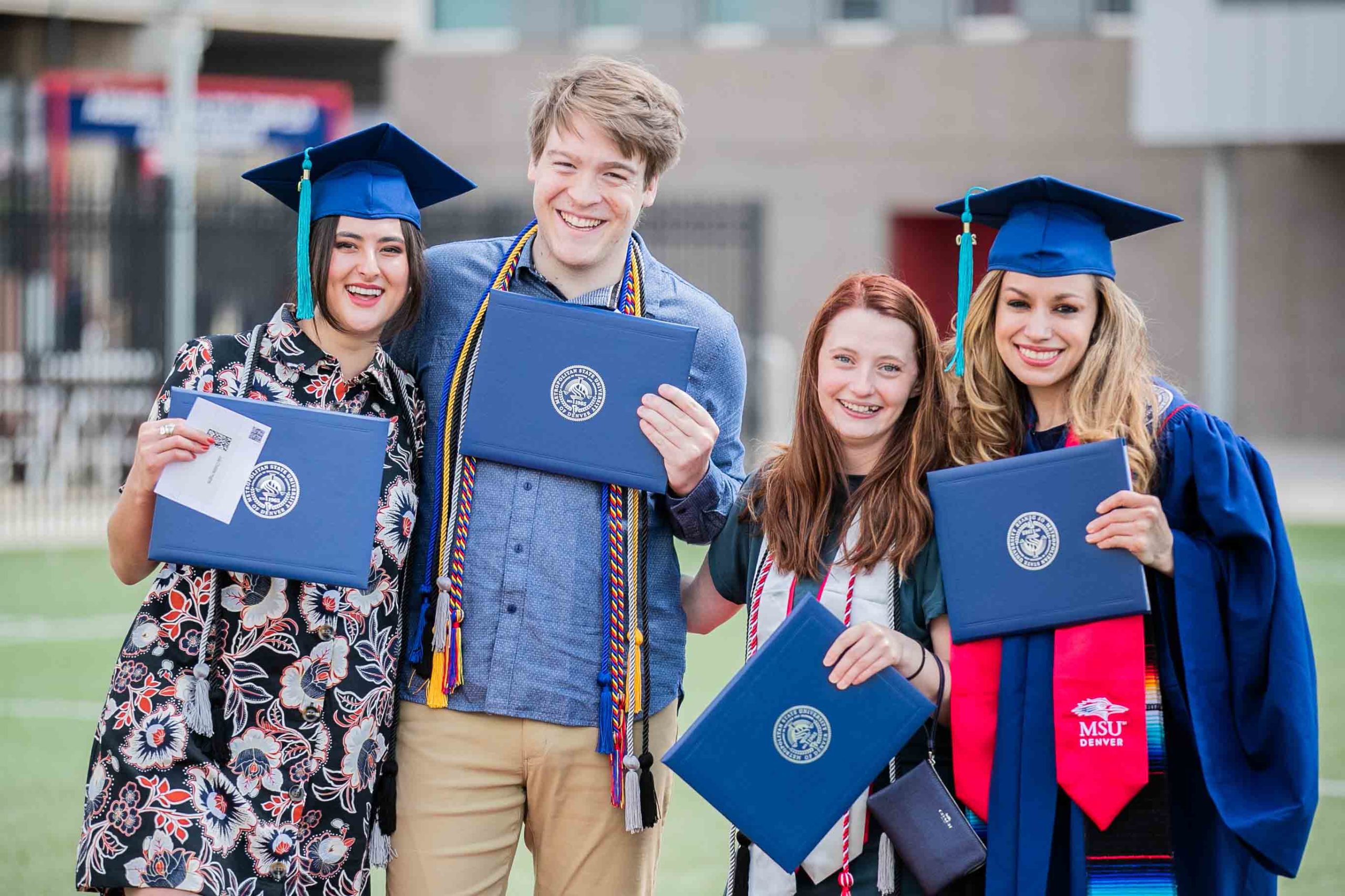 A group of graduates showing off their diploma covers as they walk towards the stage.