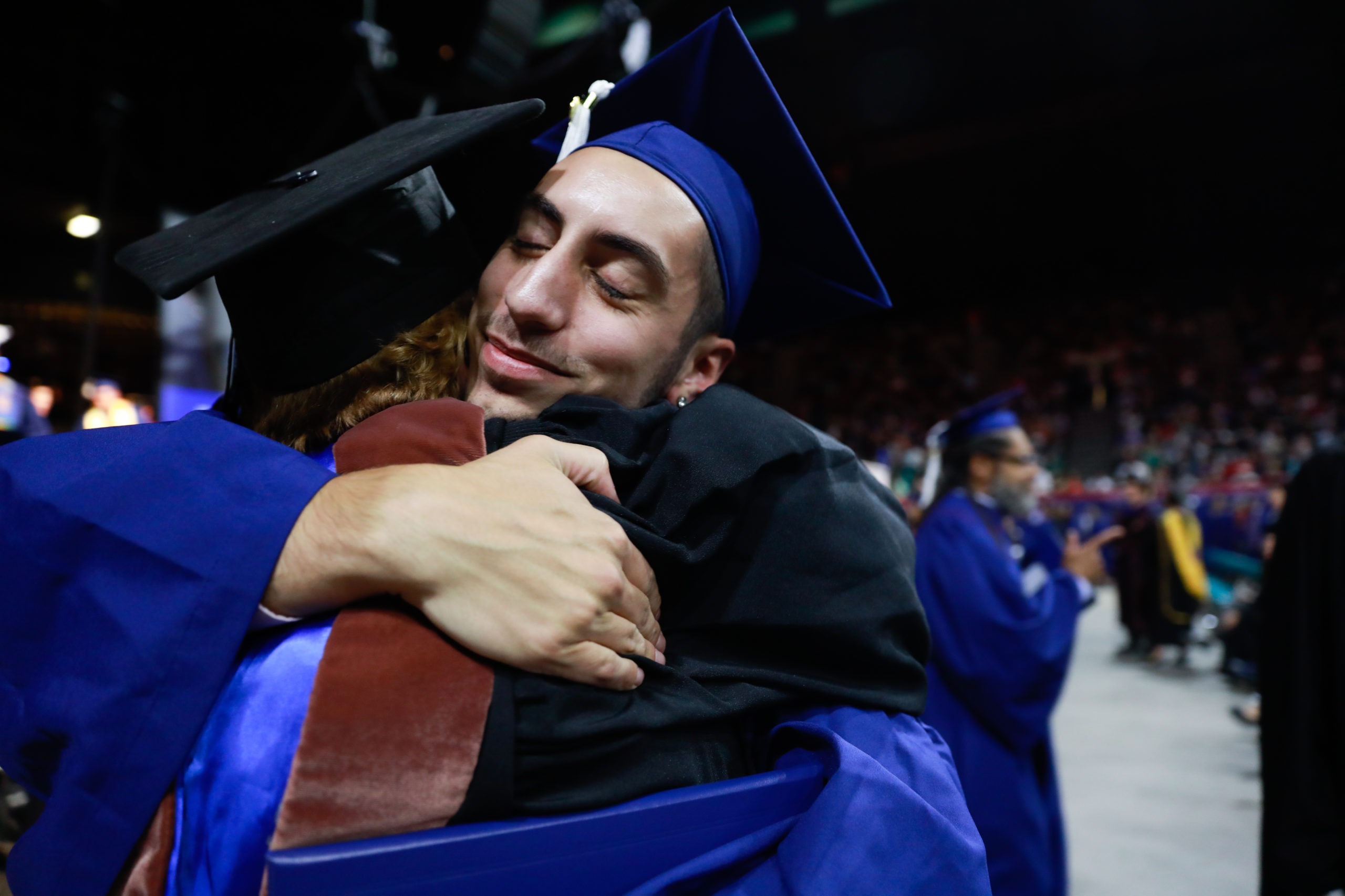 A faculty member hugs a student