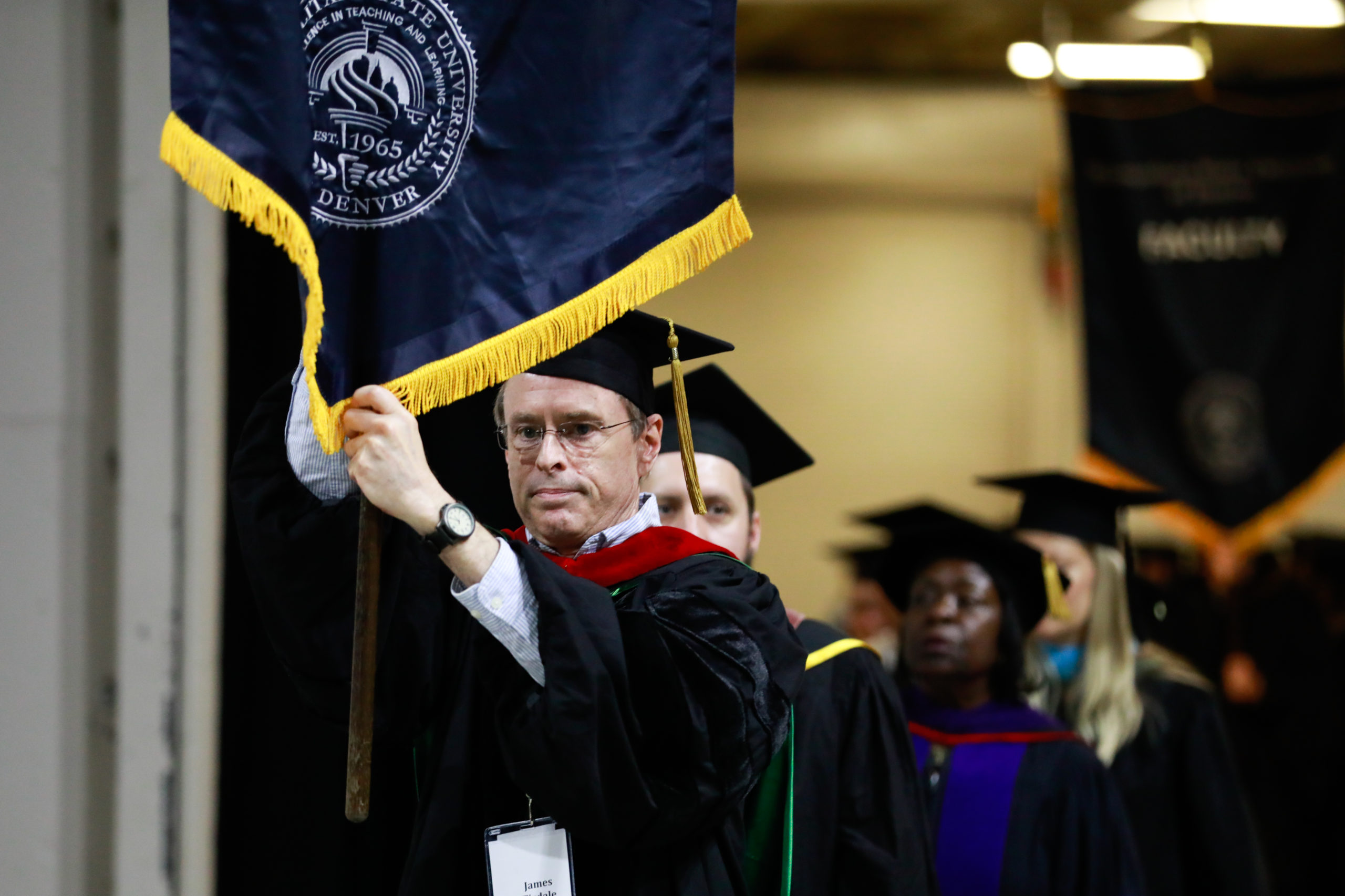 Faculty carrying banners in the coliseum floor.