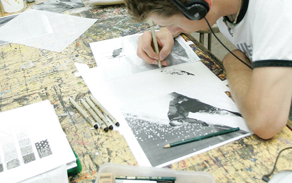 Art student draws while wearing headphones.