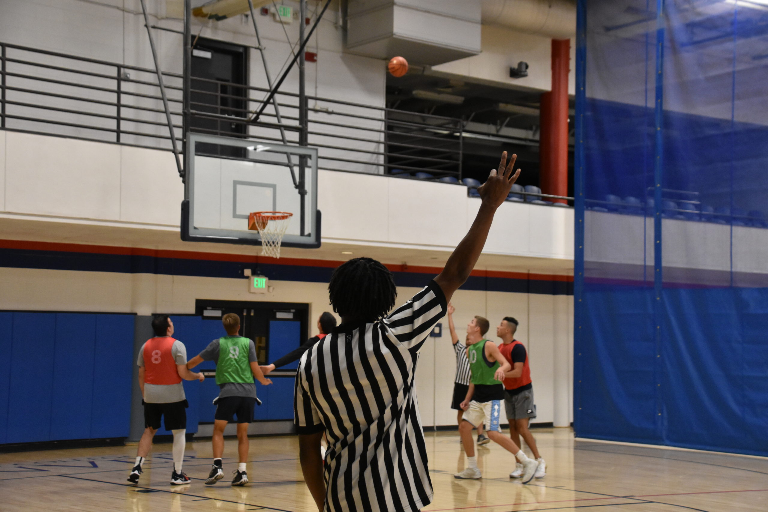 basketball official showing a 3 point attempt