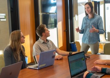 Woman at conference table with others with laptops