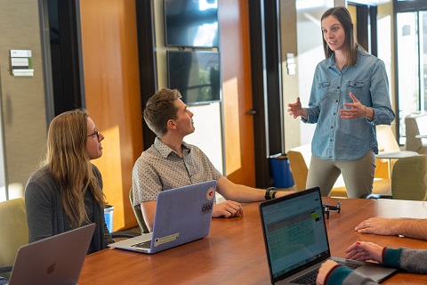 Woman at conference table with others with laptops