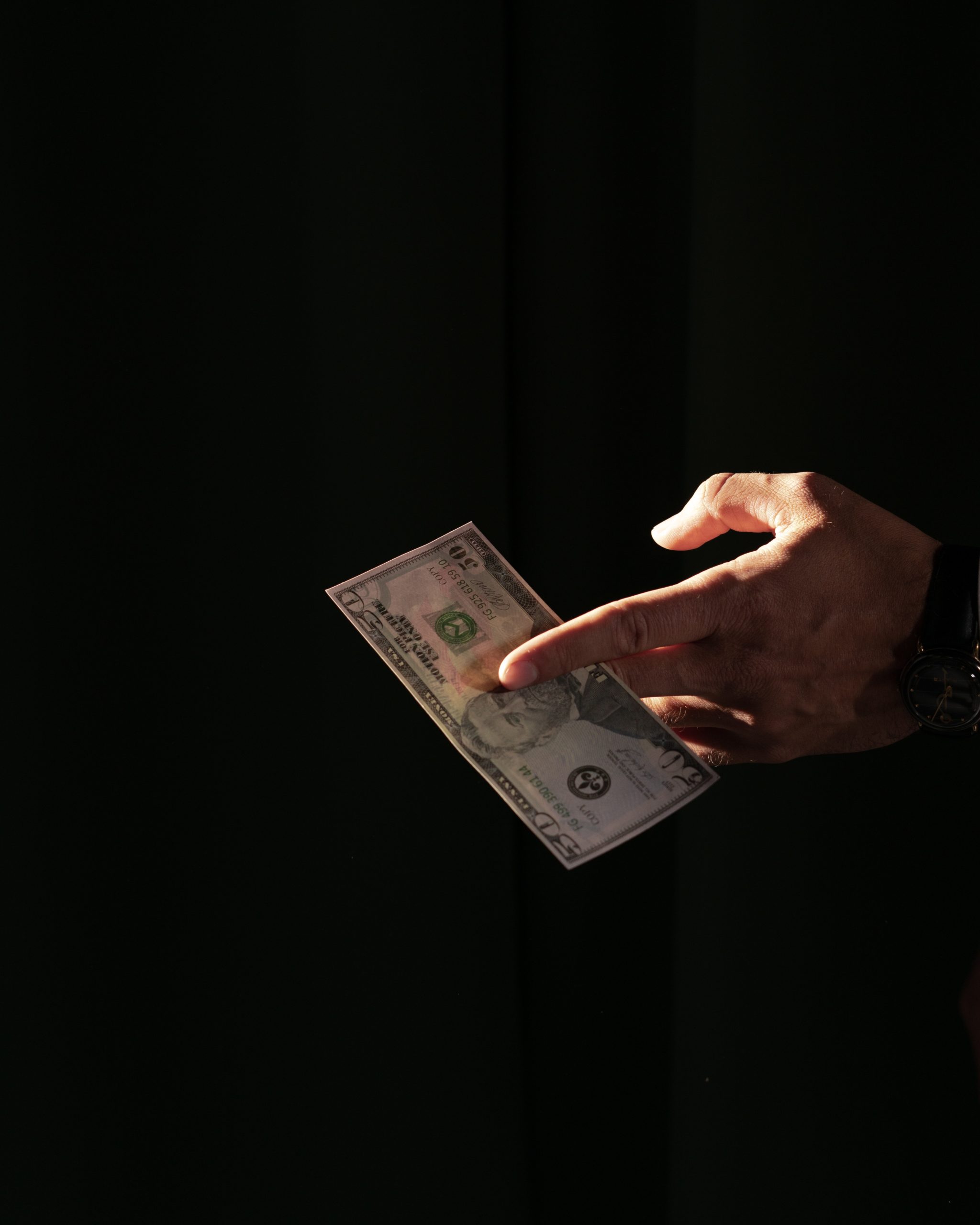 A hand presenting a $50 bill between fingers