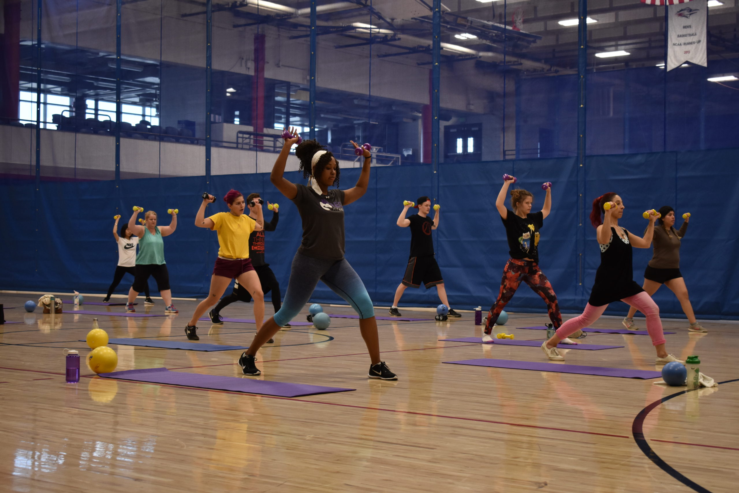 group fitness participants doing a lunging shoulder press