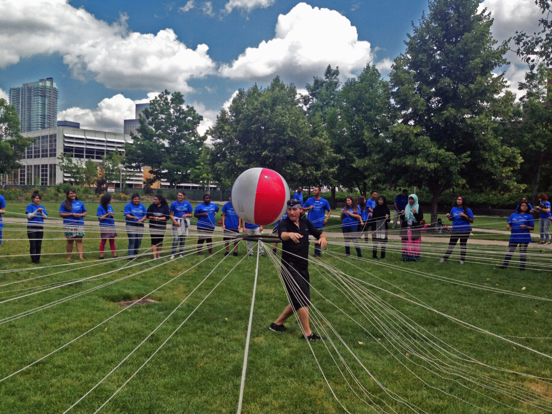 several students supporting a beach ball with string and a ring