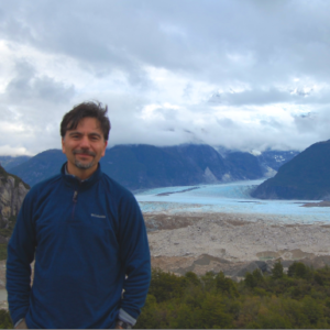 Dr. Antonio Bellisario standing in front of a waterway cutting through mountains