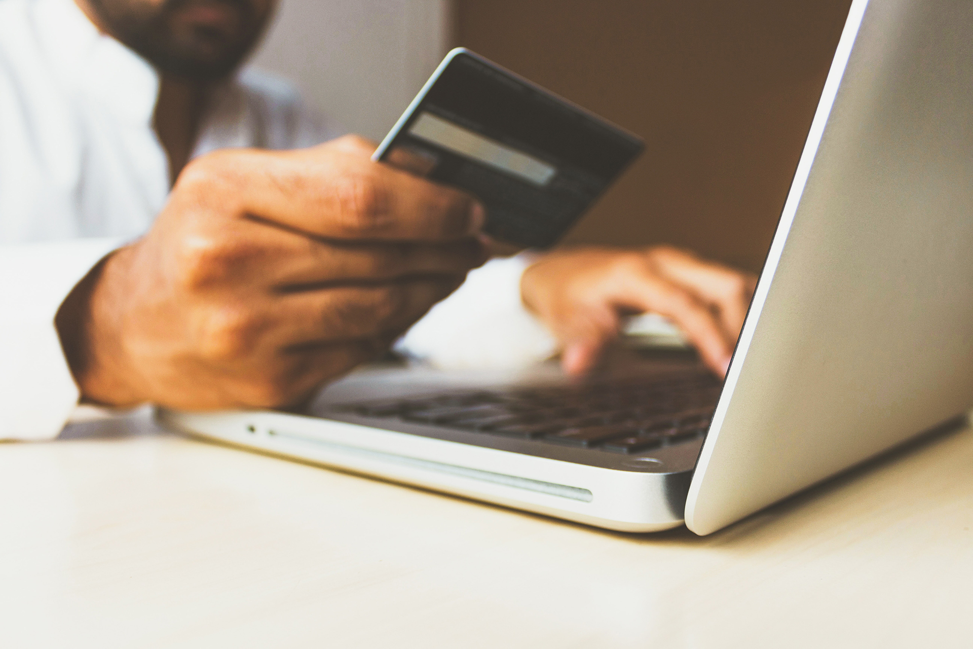 Person looking at credit card while working on a computer. Concept of an online purchase.