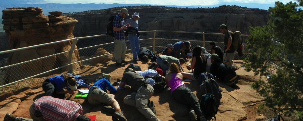 Geology students inspect the geology of the top of a cliff