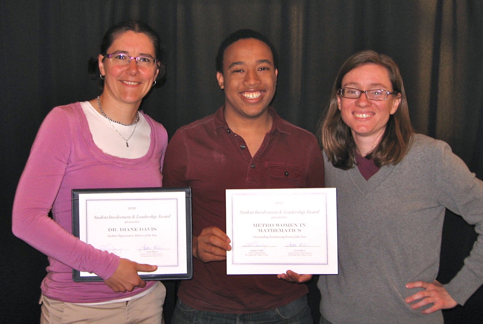 Three people standing and holding certificates