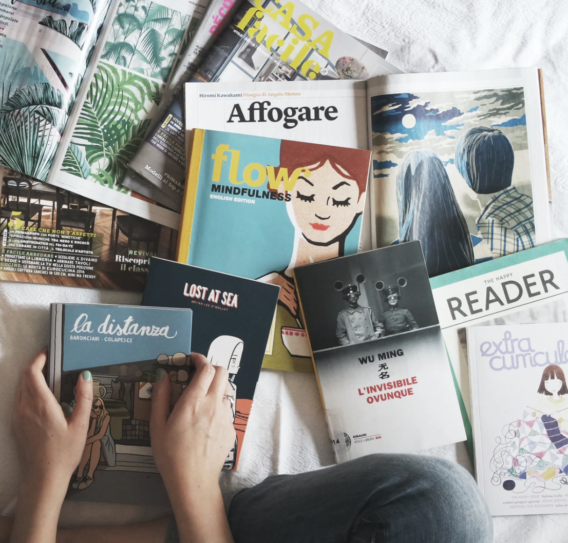 A small pile of scattered magazines on a bed.