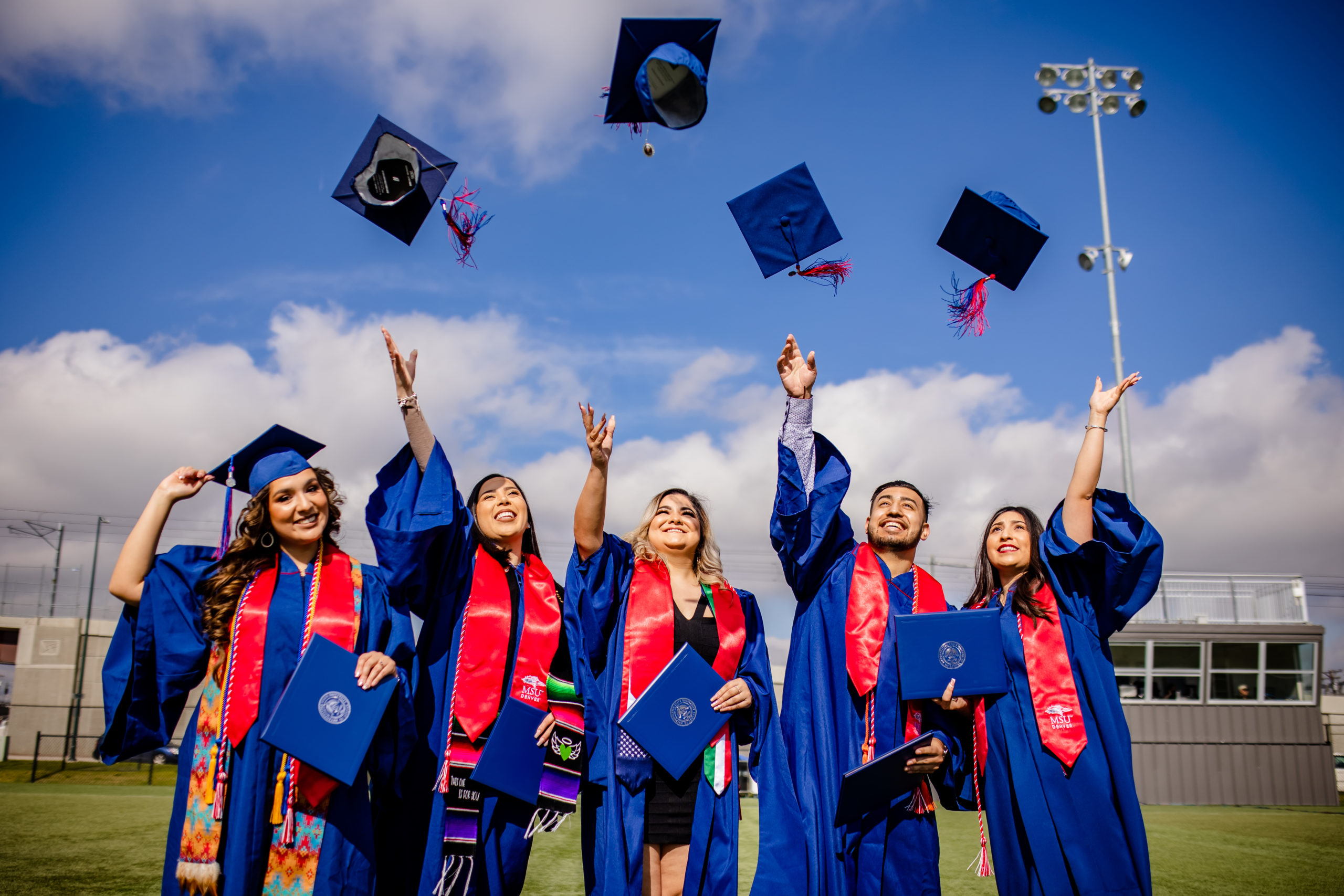 MSU Denver students celebrating graduating by throwing their graduation caps in the air