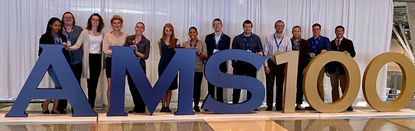 Students posing in front of the AMS 100 sign at AMS Boston in 2020