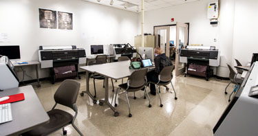 A wide view of the Photography Studio showing desks, computer workstations and large format printers.