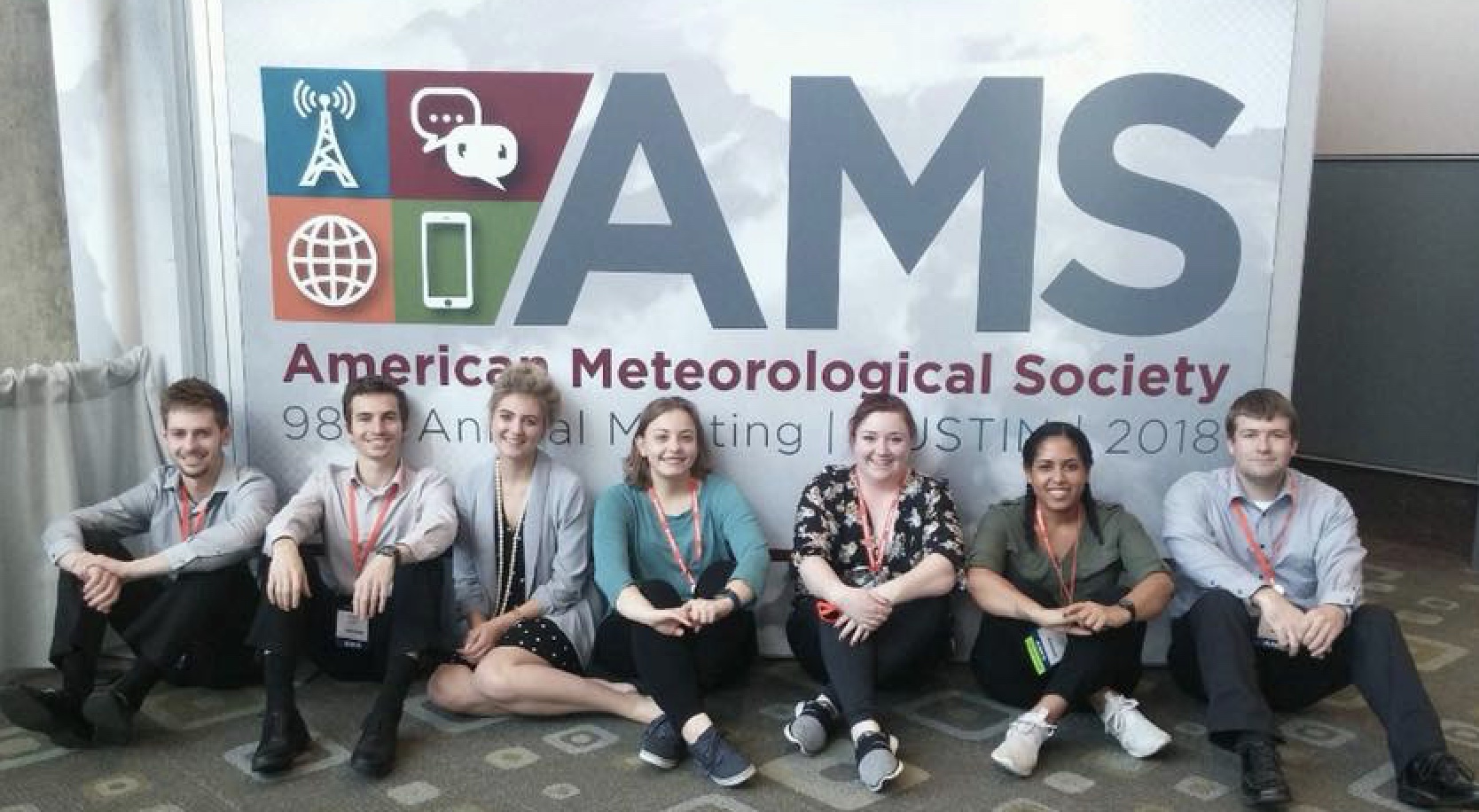 Students sitting in front of the AMS sign