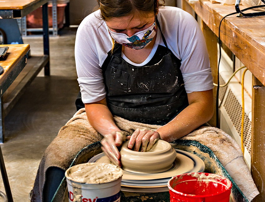 Woman spinning a bowl on the pottery wheel