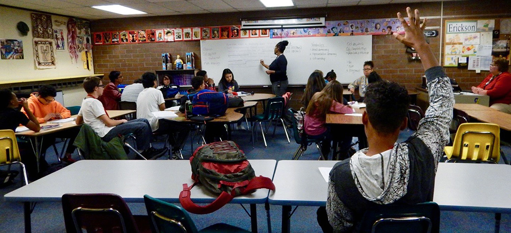 Photograph of a teacher instructing children in a classroom.