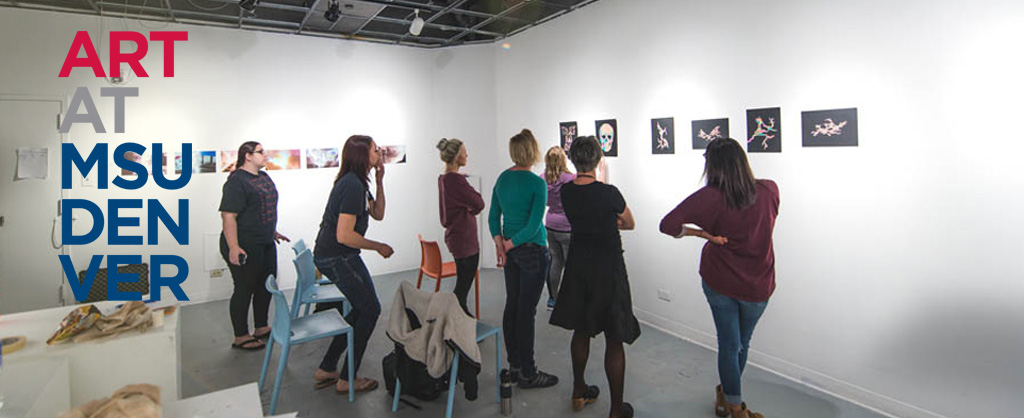 Students examining artwork on the wall of the studio