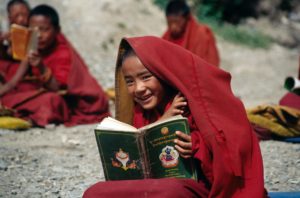 Picture of a smiling boy reading a buddhist text