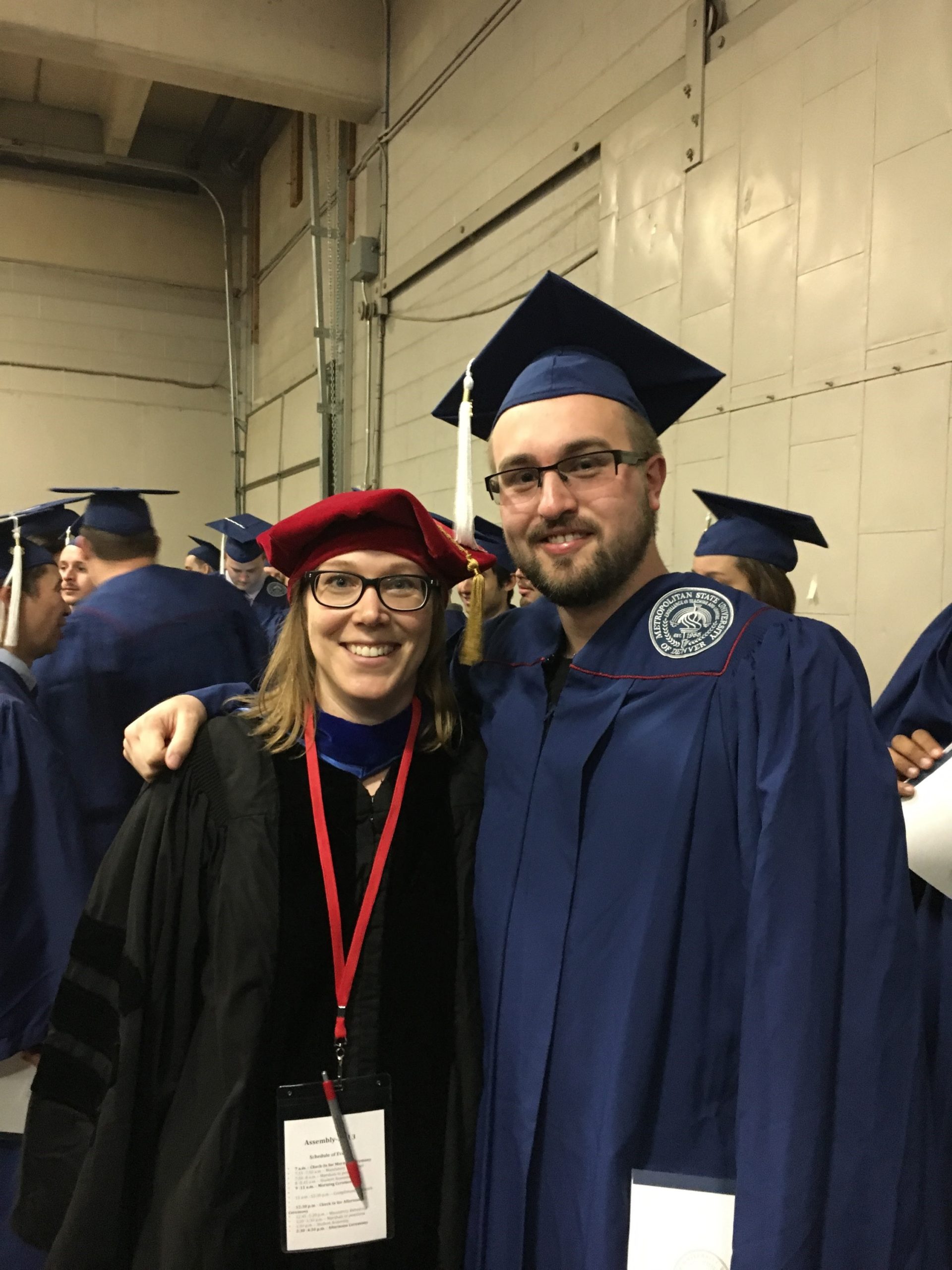 Cody Griffith in a cap and gown, posing with a professor