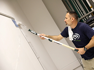 A volunteer painting a classroom wall.
