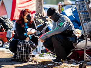 An addiction counselor treating a citizen at a homeless encampment.
