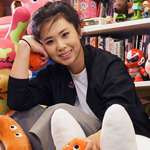 Sharon Park sitting around stuffed animals, toys, and book shelf