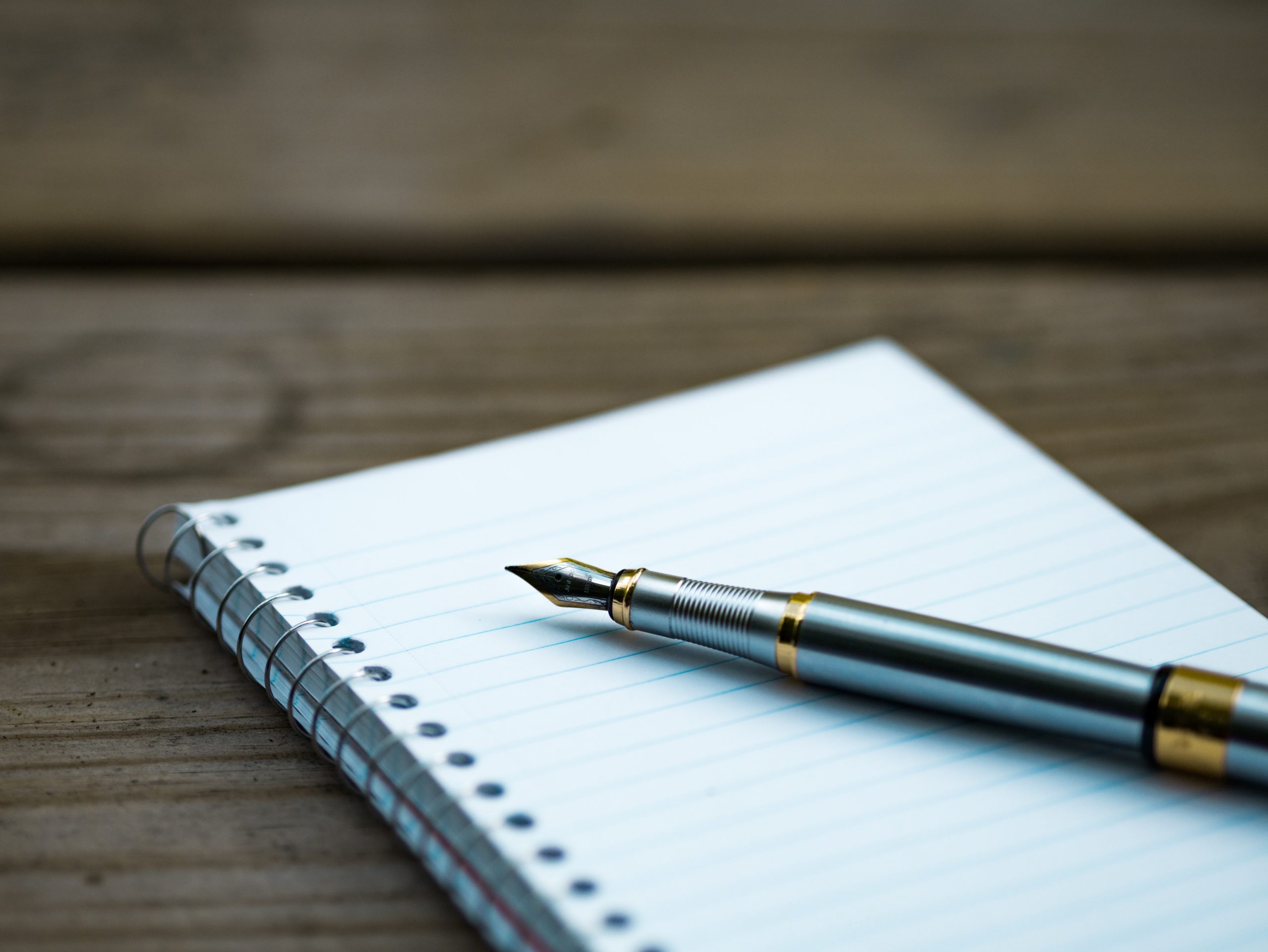 A fountain pen sitting on a pad of paper