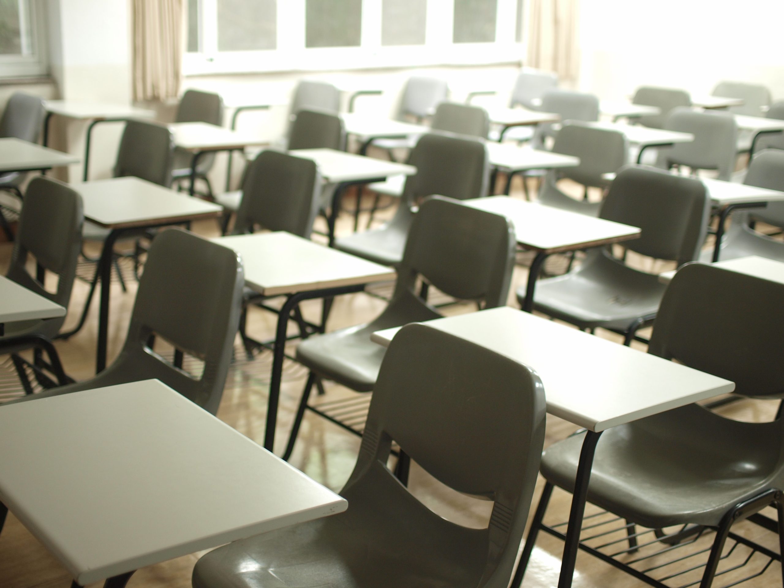 Rows of empty desks and chairs in a classroom
