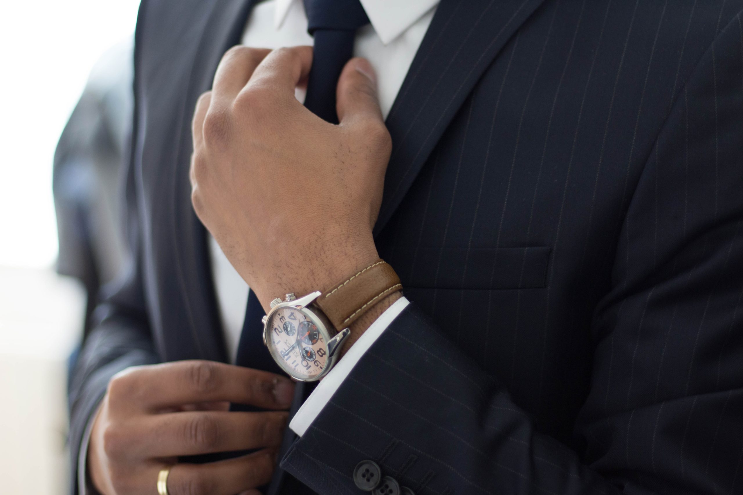 A person wearing a watch adjusting their tie